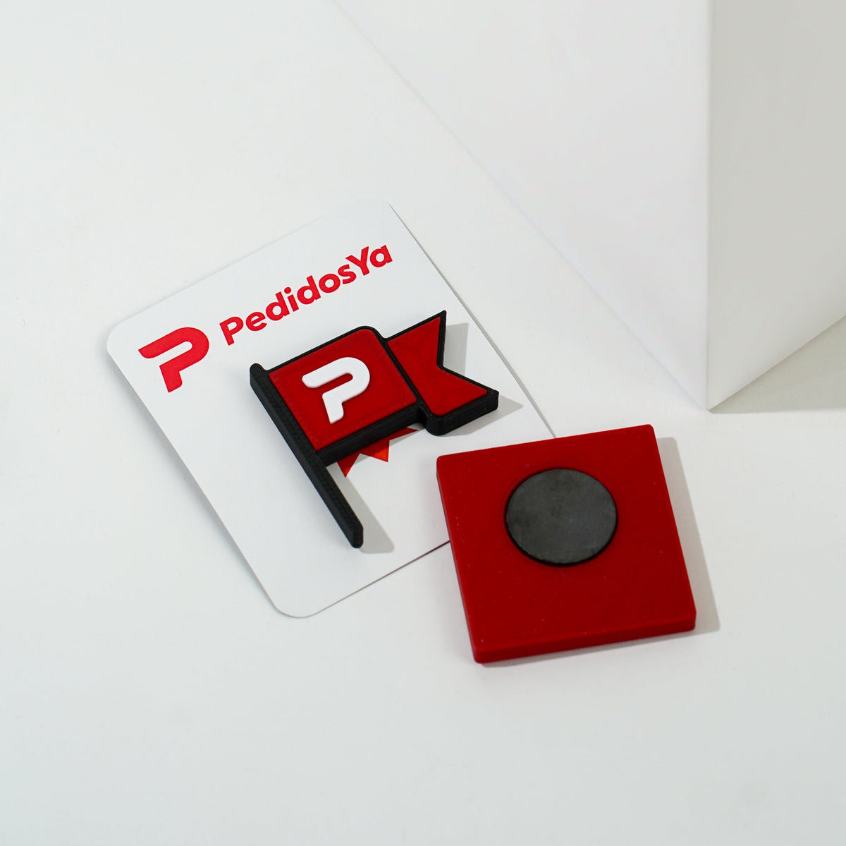 Imán corporativo personalizado de PedidosYa fabricado en impresión 3D, con diseño de bandera y base magnética para uso promocional
