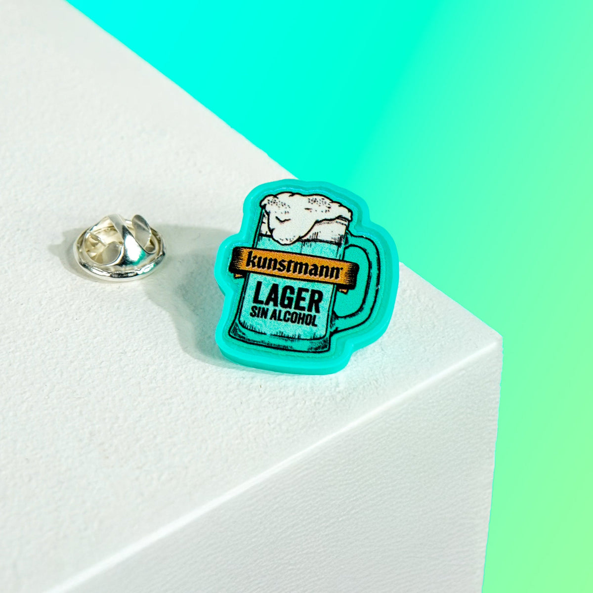 Pin publicitario personalizado de Kunstmann, fabricado en impresión 3D, con relieves definidos, alta fidelidad de color y acabado premium.